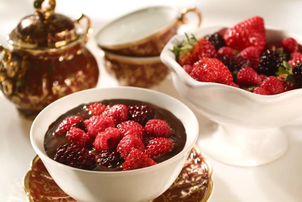 Sobremesas servidas em louça branca com frutas vermelhas
